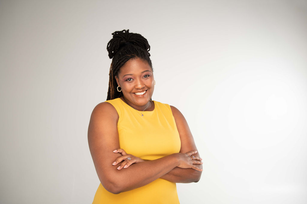 Co-founder of The Superwoman Retreat, Jasmine Garland, smiling in a yellow dress in front of a white background